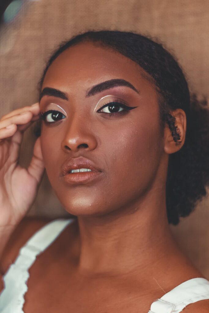 Close-up portrait of a young woman showcasing bold makeup with eyeliner and a serene expression.