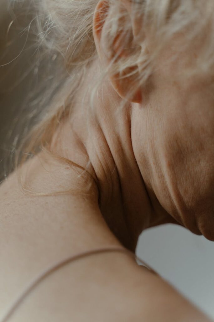 Detailed view of an elderly woman's neck, showcasing aging skin and natural wrinkling.