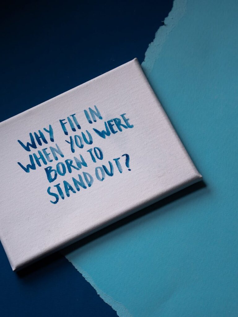 Canvas with motivational quote 'Why fit in when you were born to stand out?' on a blue backdrop.