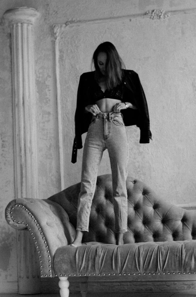 Stylish woman on a vintage sofa, captured in black and white, showcasing modern fashion.