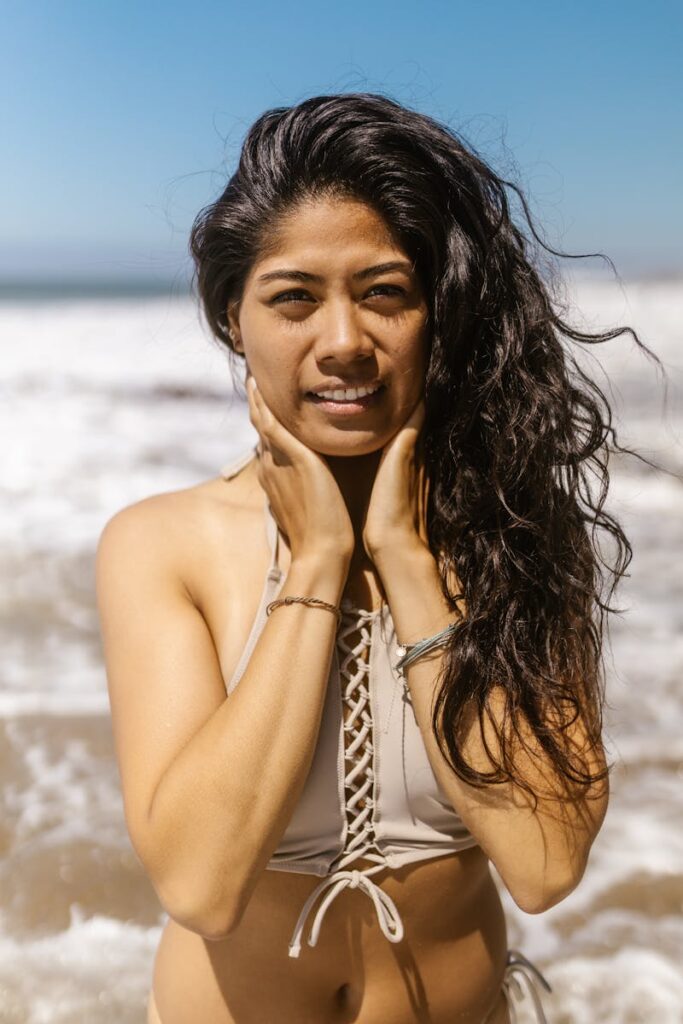 A young woman enjoys the sunny beach, wearing stylish swimwear with a relaxed expression.