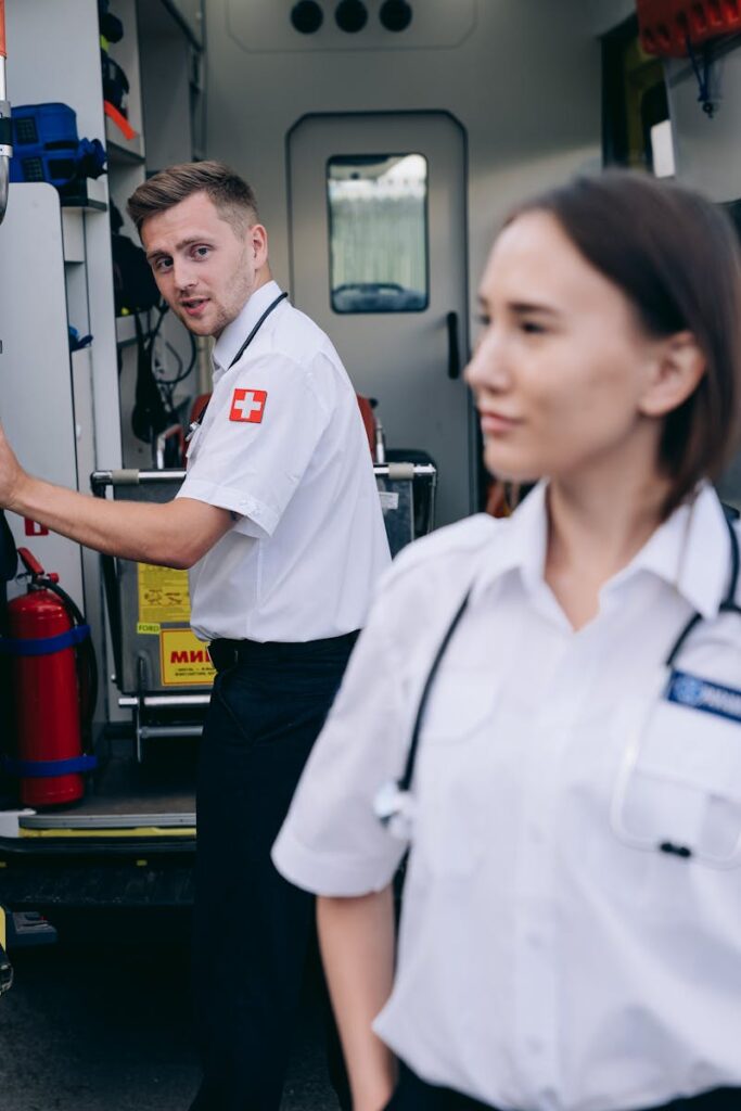 Two paramedics in uniform at an ambulance ready for emergency service.