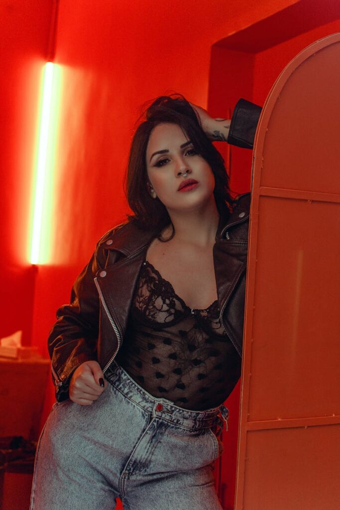A fashionable woman posing indoors in a leather jacket and lace top.
