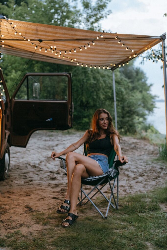 Woman sitting outdoors under a canopy with lights, enjoying a summer vibe.