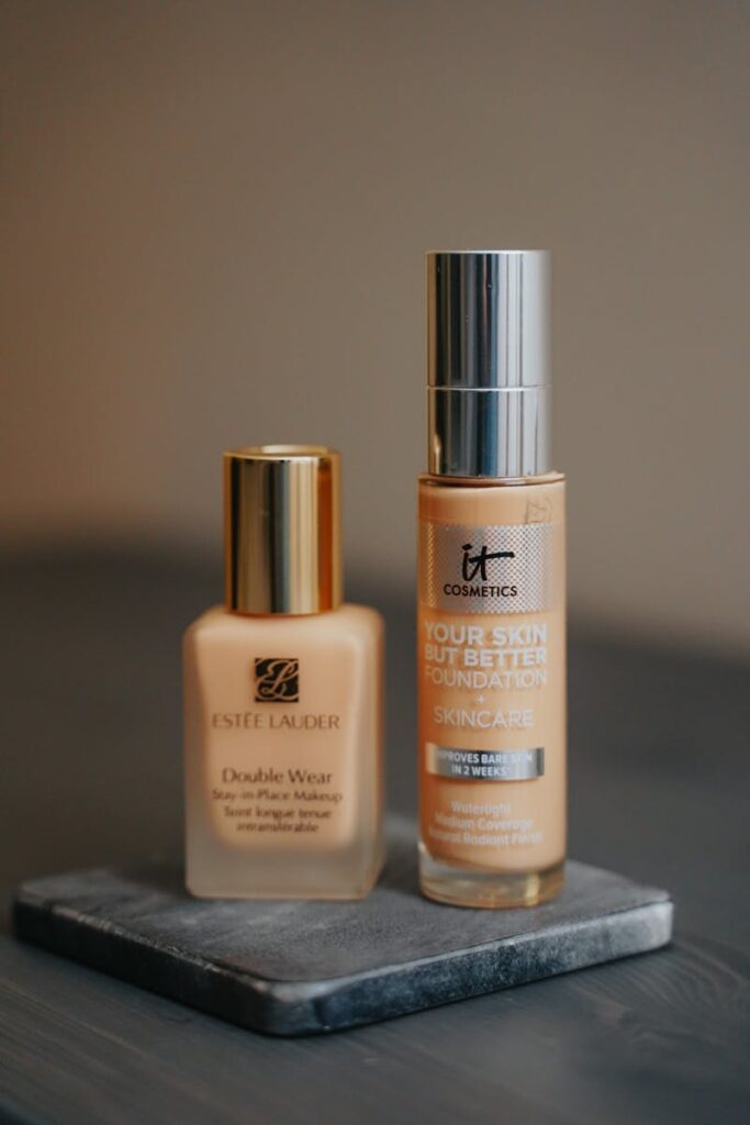 Close-up of Estee Lauder and IT Cosmetics foundations on a stone surface.