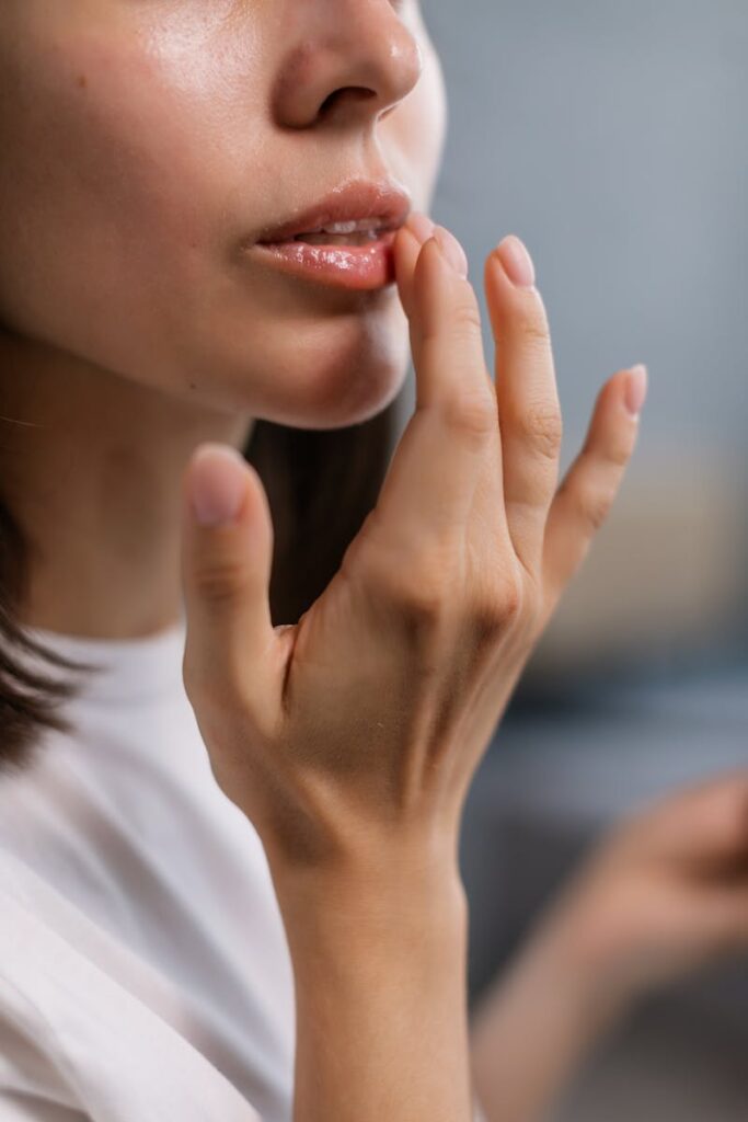Close-up of a woman's hand applying lip balm, highlighting beauty care routine.