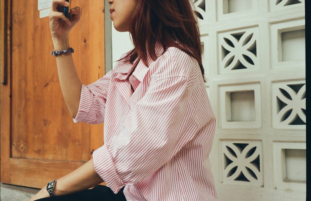 A woman sitting on the ground taking a picture with her cell phone