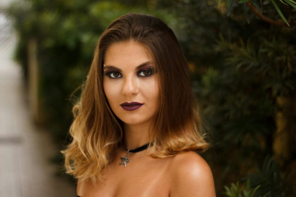 Elegant portrait of a woman with smokey makeup, bold lipstick, and an alluring stare.