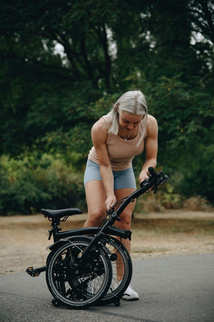 Caucasian woman setting up a folding bike outdoors on a sunny day.