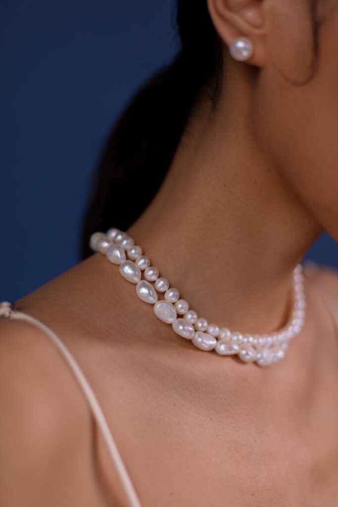 Close-up of a woman's neck adorned with a luxurious pearl necklace and matching earring.