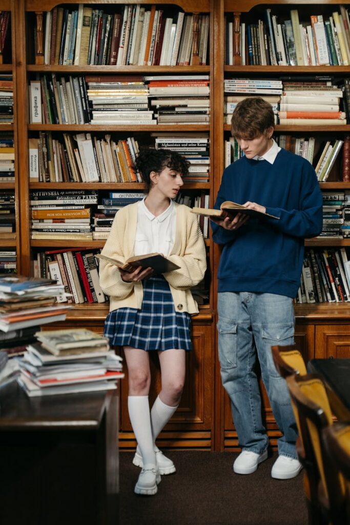 Two students reading in a library surrounded by books, symbolizing learning and education.