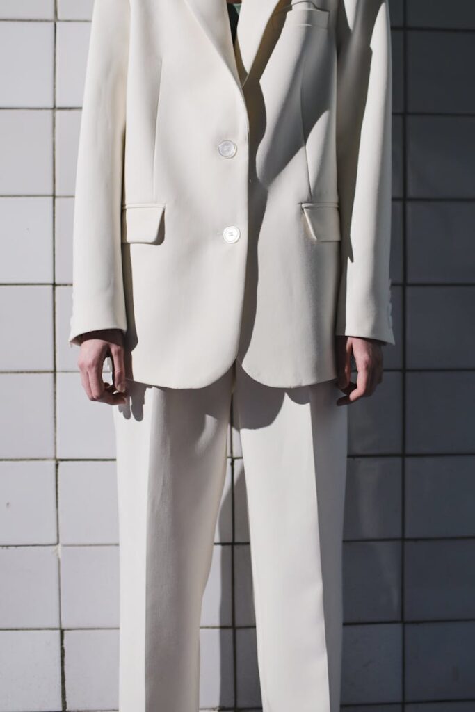 Elegant white suit fashion photography with a minimalist tiled backdrop, highlighting contemporary style.