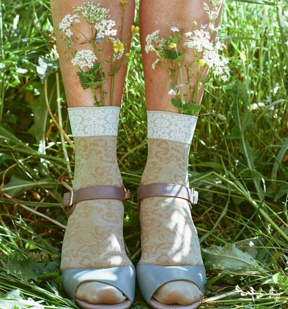 Creative display of flowers in socks worn with sandals in a sunny meadow.