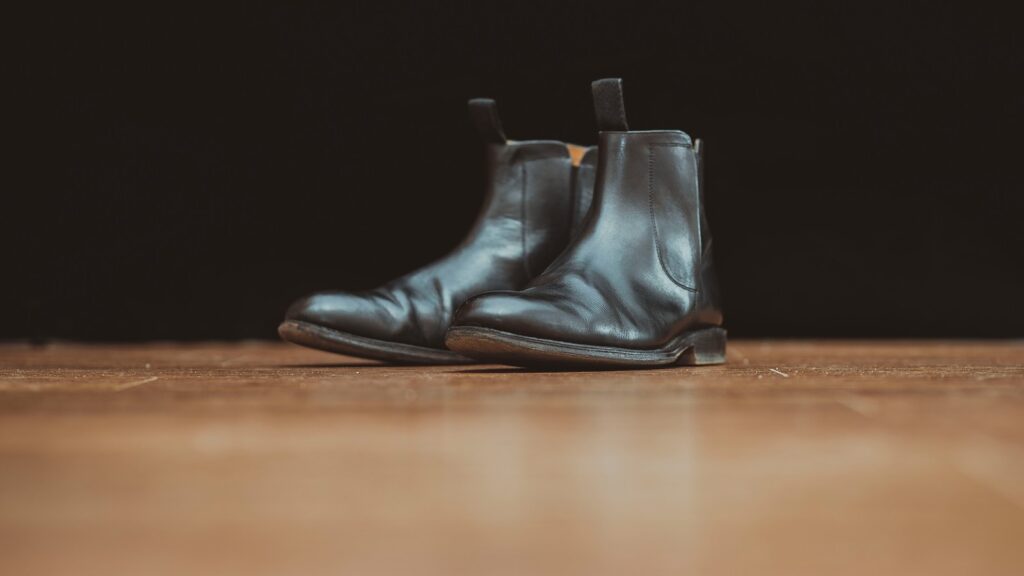 pair of black leather boots on brown surface