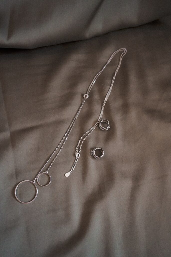 silver necklace on white textile