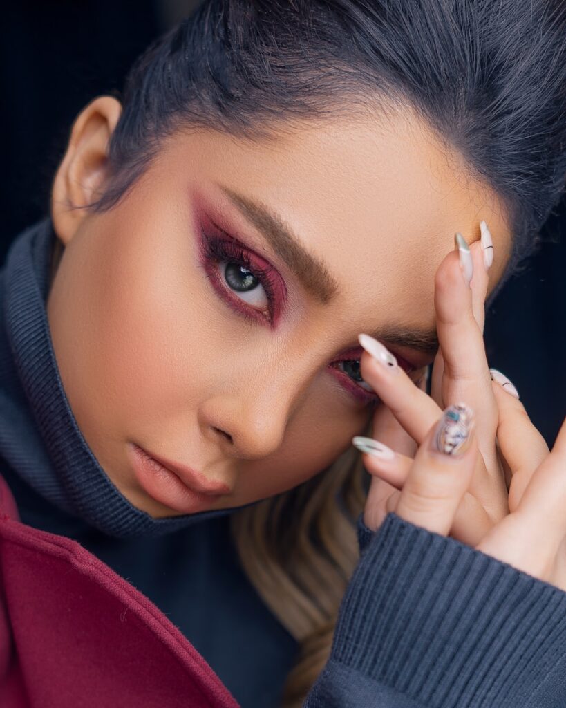 woman in red jacket covering her face with her hand