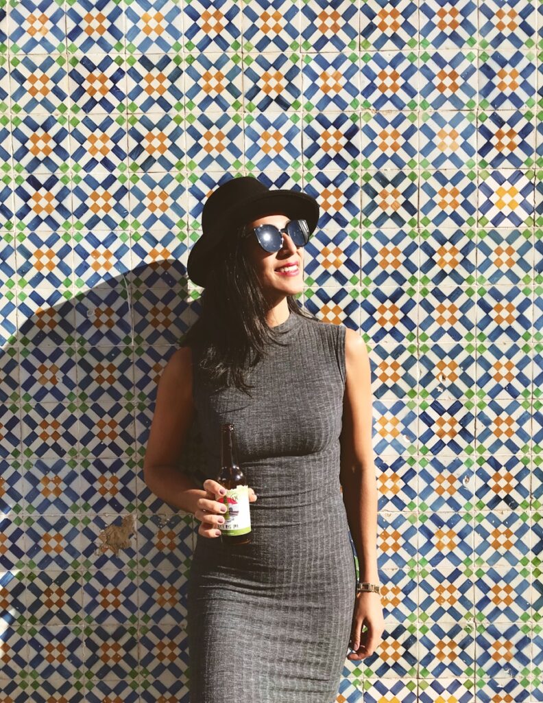 woman standing near the wall while holding beer bottle