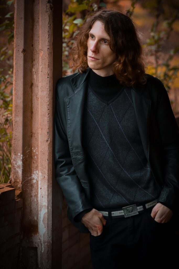 woman in black leather jacket standing beside brown wooden post during daytime