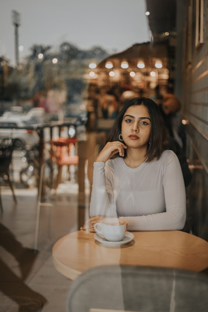 a woman sitting at a table with a cup of coffee