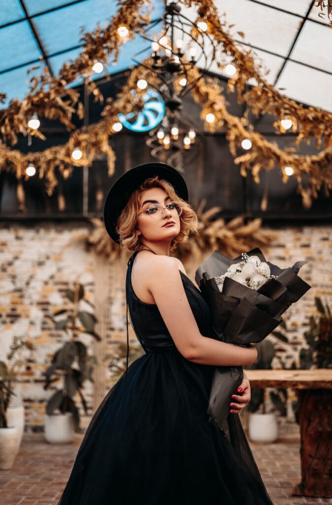 woman in black sleeveless dress holding white and black floral handbag