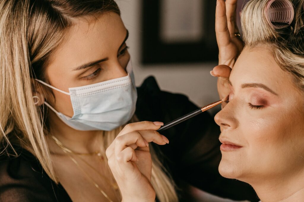 a woman getting her makeup done by another woman
