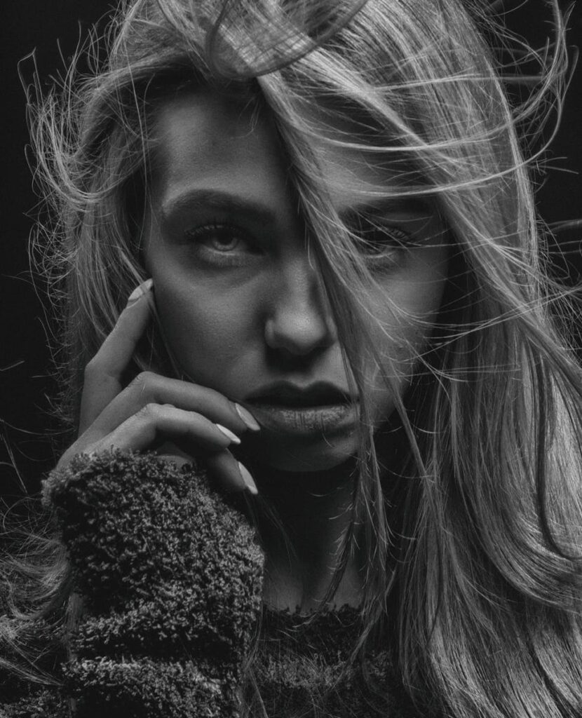 Elegant monochromatic portrait of a woman with wind-swept hair and intense gaze.