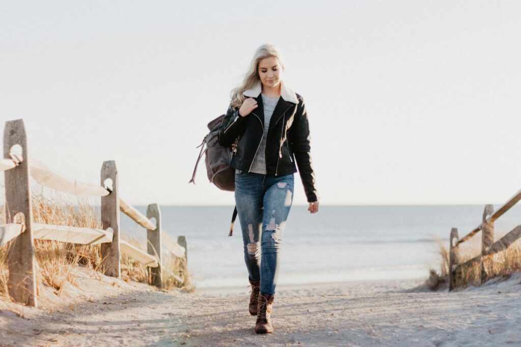 Stylish woman in leather jacket walking by the ocean in Ocean City, NJ.