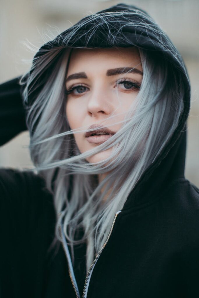 Close-up portrait of a fashionable woman with striking silver hair and black hoody.