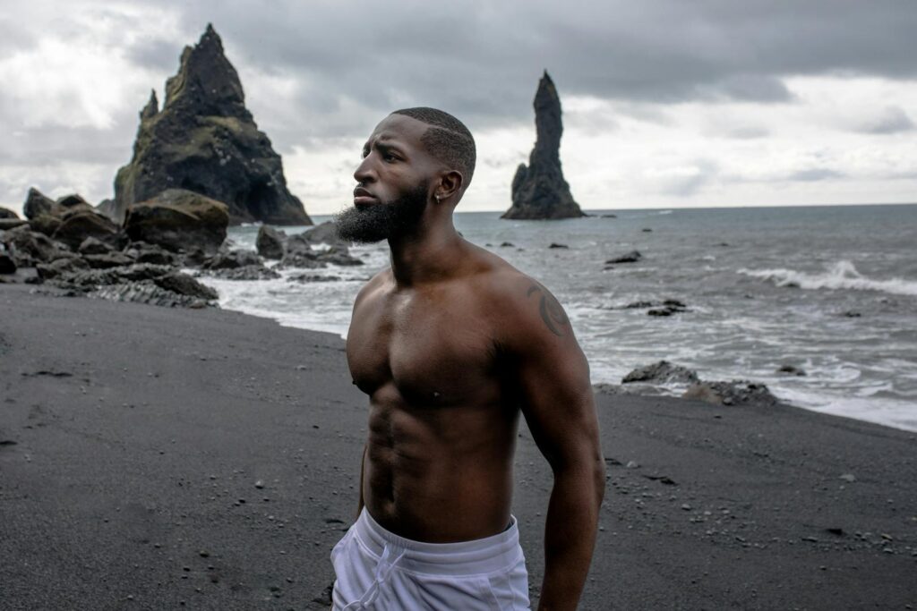 Muscular man on Reynisfjara's black sands, Iceland beauty.