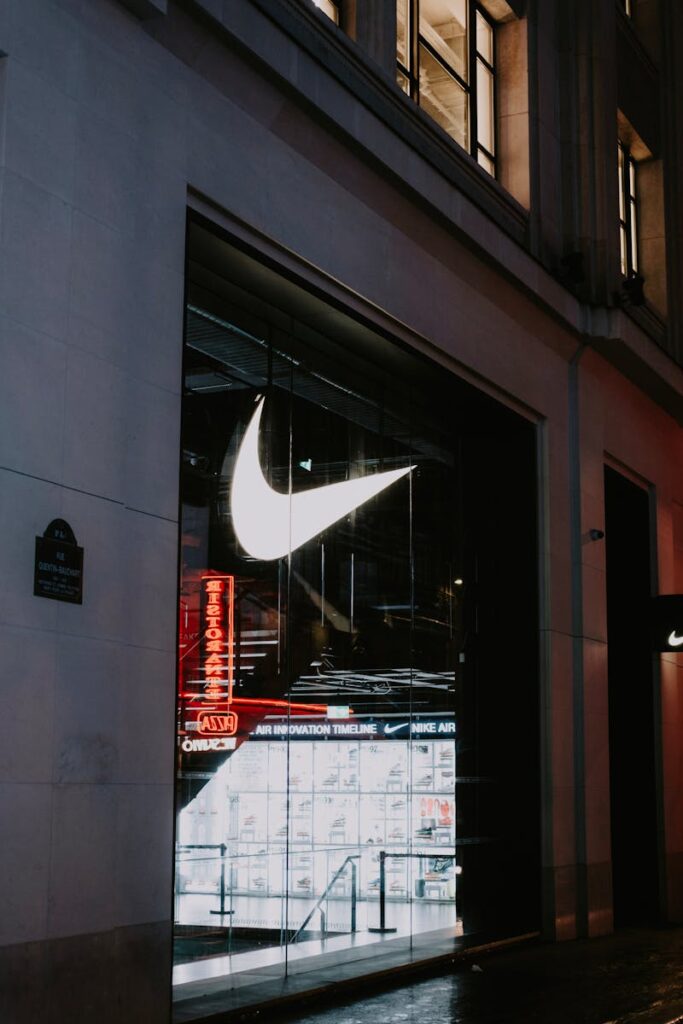 Nike store facade with glowing logo and modern glass exterior, captured at night.