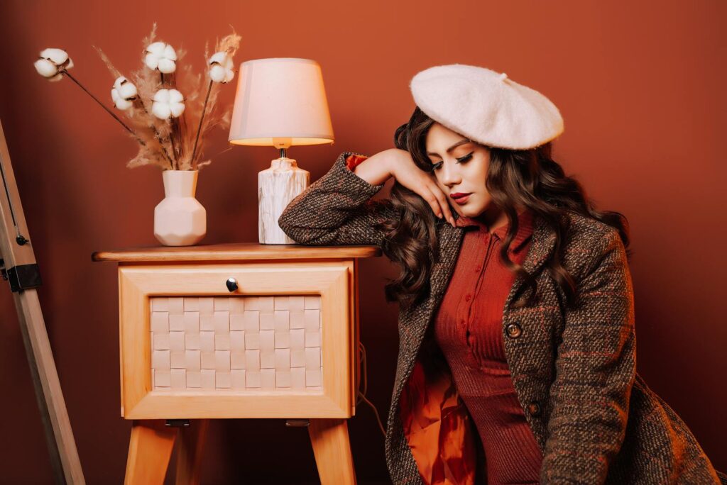 Fashionable woman in retro attire beside cozy vintage decor with warm tones.