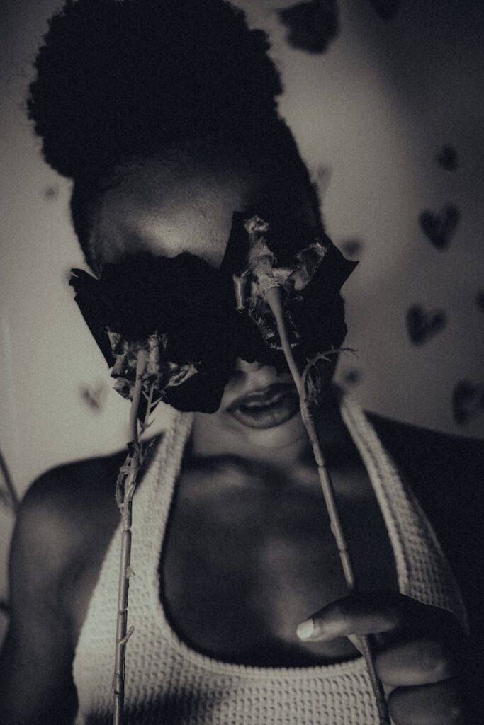 Striking monochrome portrait of a woman with roses covering her eyes, evoking mystery and artistry.