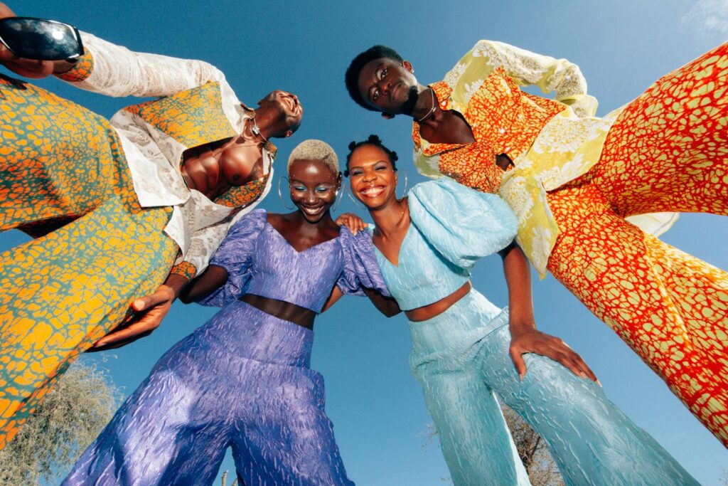 Joyful group wearing bold, colorful African fashion outdoors on a sunny day.