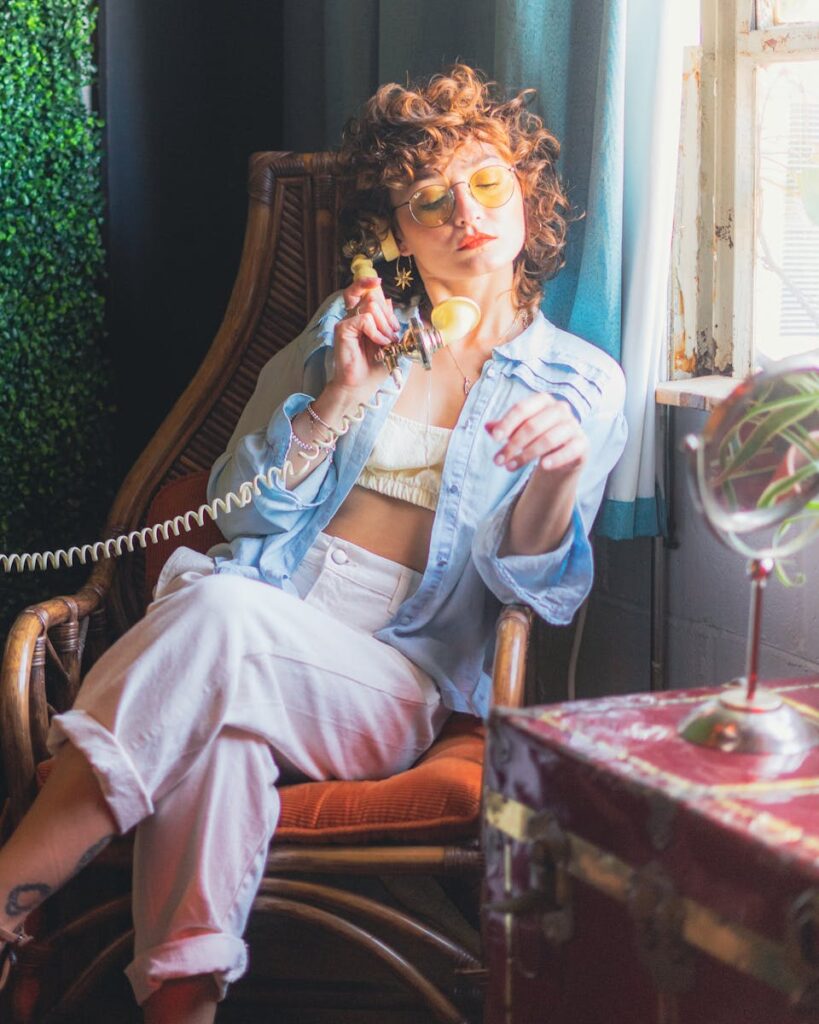 Fashionable woman in vintage setting, talking on a retro telephone with a relaxed and stylish pose.