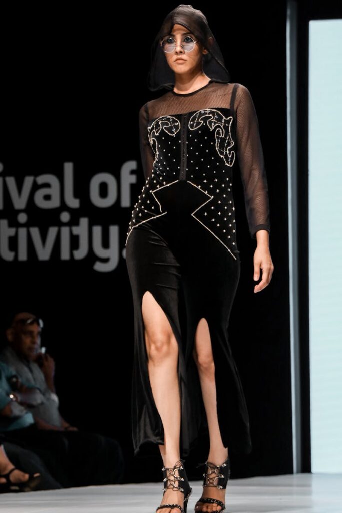 Fashion model showcasing a stylish black dress at a runway event.