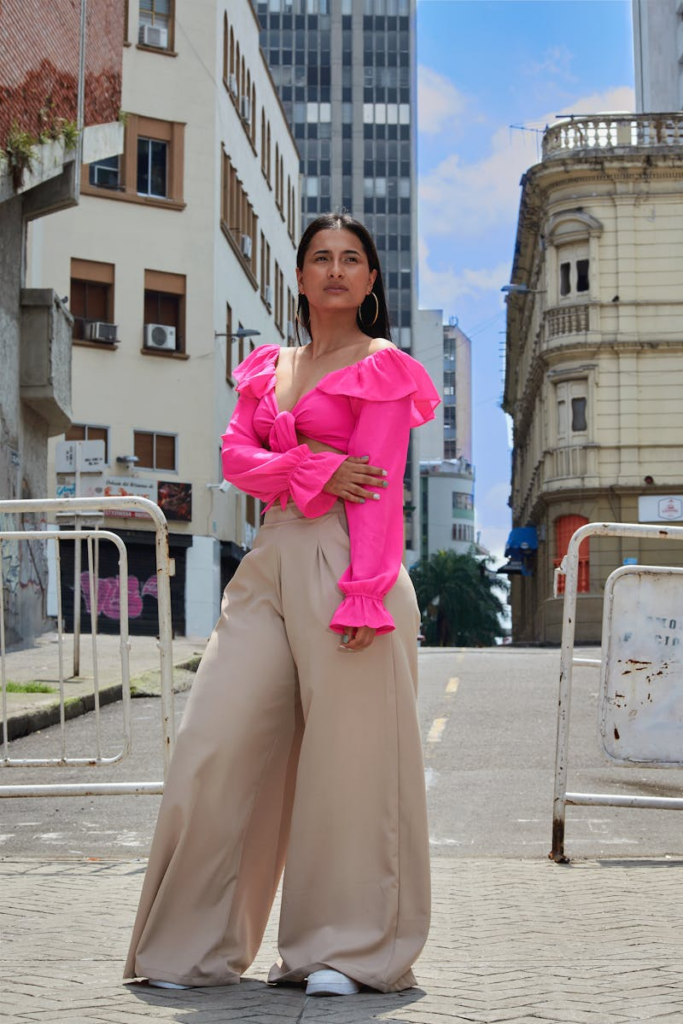 Stylish woman in city wearing vibrant outfit, standing confidently on street with architectural backdrop.