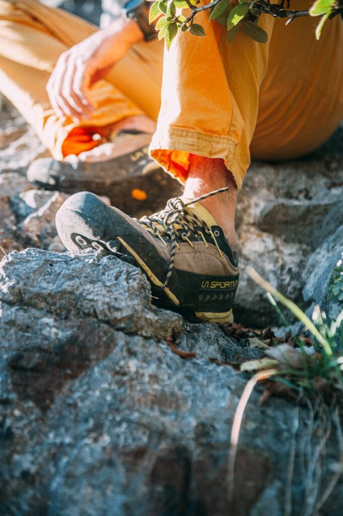 A close-up of hiker's shoe and leg on a rocky terrain in sunlight.