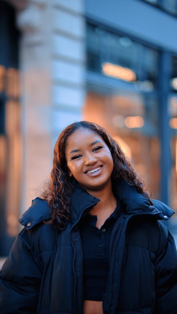 Smiling young woman in a warm jacket enjoying a winter day in the city.