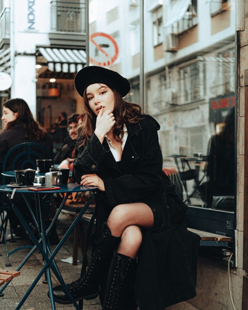Elegant brunette woman in a beret enjoying coffee at an outdoor café table.