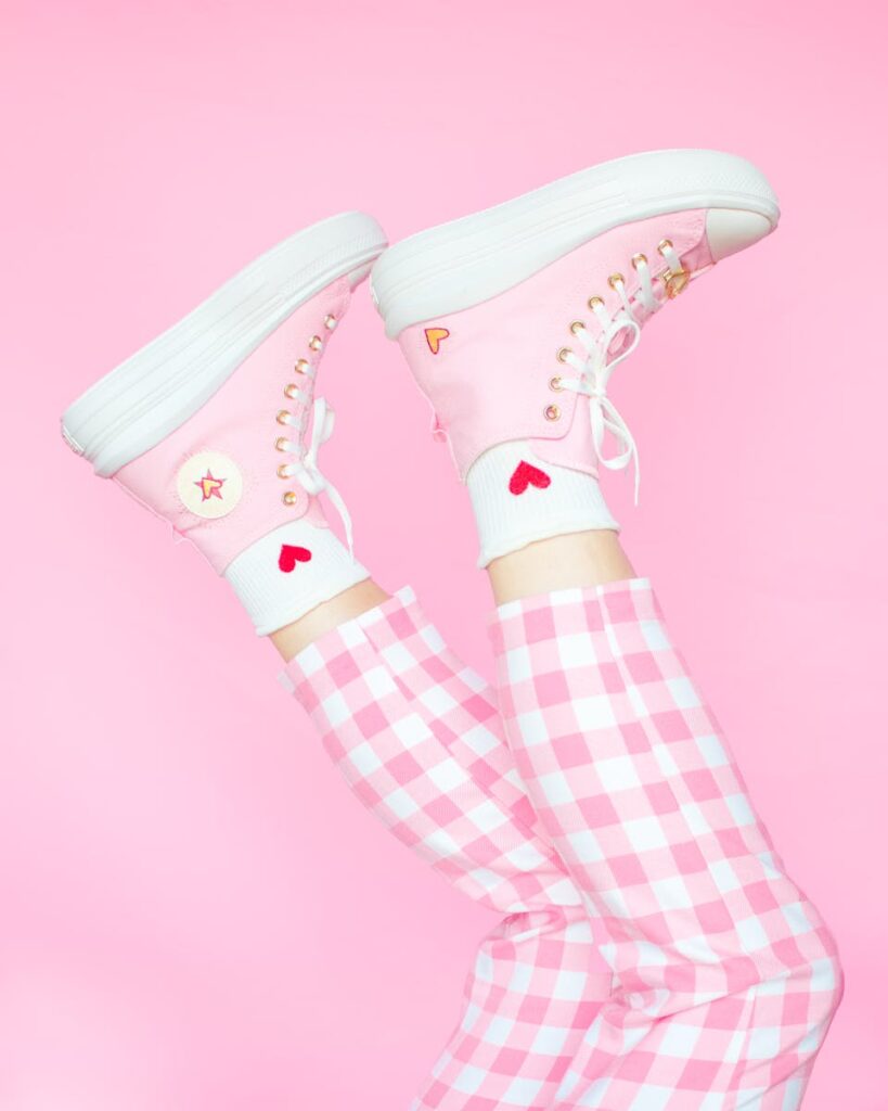 Trendy pink sneakers and checkered pants on a vibrant pink background.