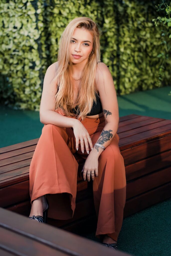 Stylish woman with blonde hair posing in wide-leg pants, São Paulo outdoor setting.