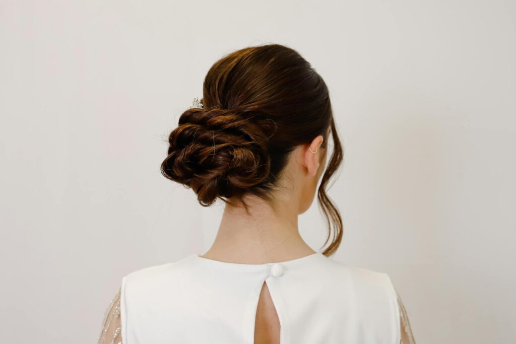 Elegant bridal hairstyle featuring an intricate bun on a woman in white attire.