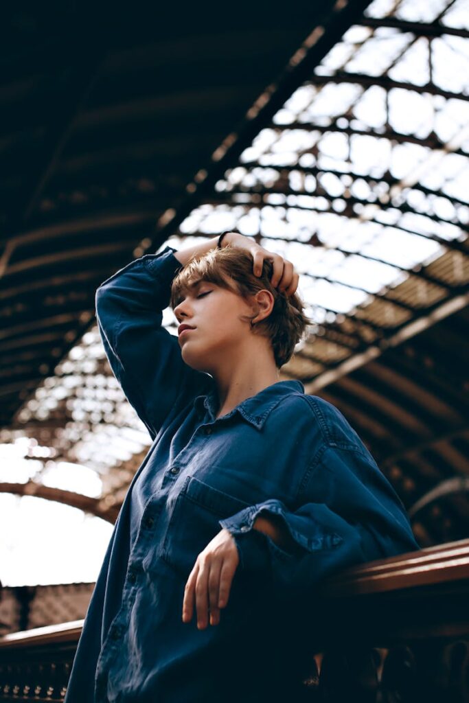Thoughtful woman in blue with short hair poses in dramatic architectural background.