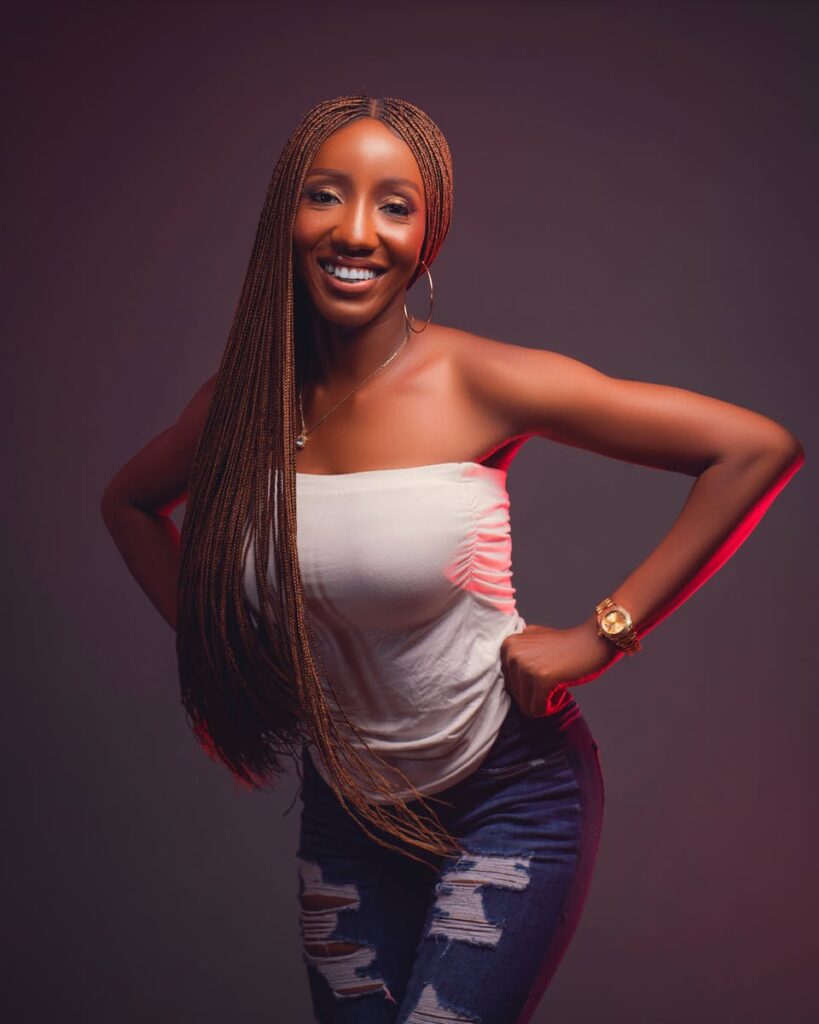 Smiling woman with braids posing confidently in a studio with strapless top.