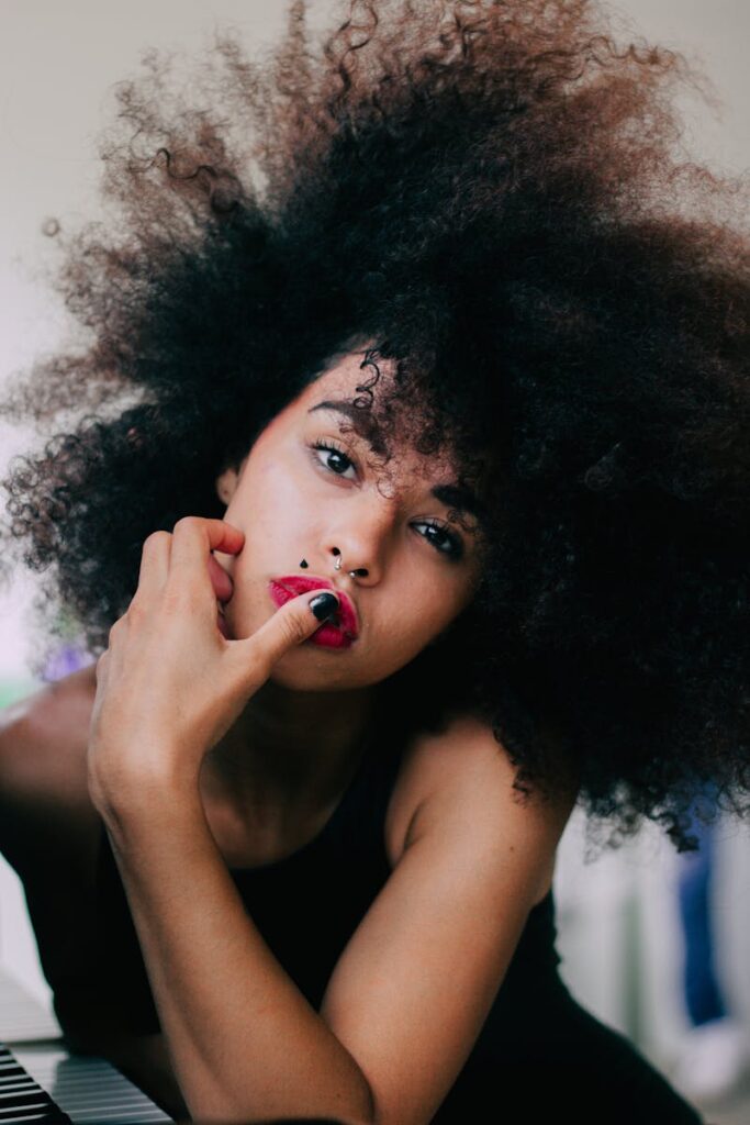 Close-up portrait of a beautiful woman with vibrant curly hair and bright red lipstick.