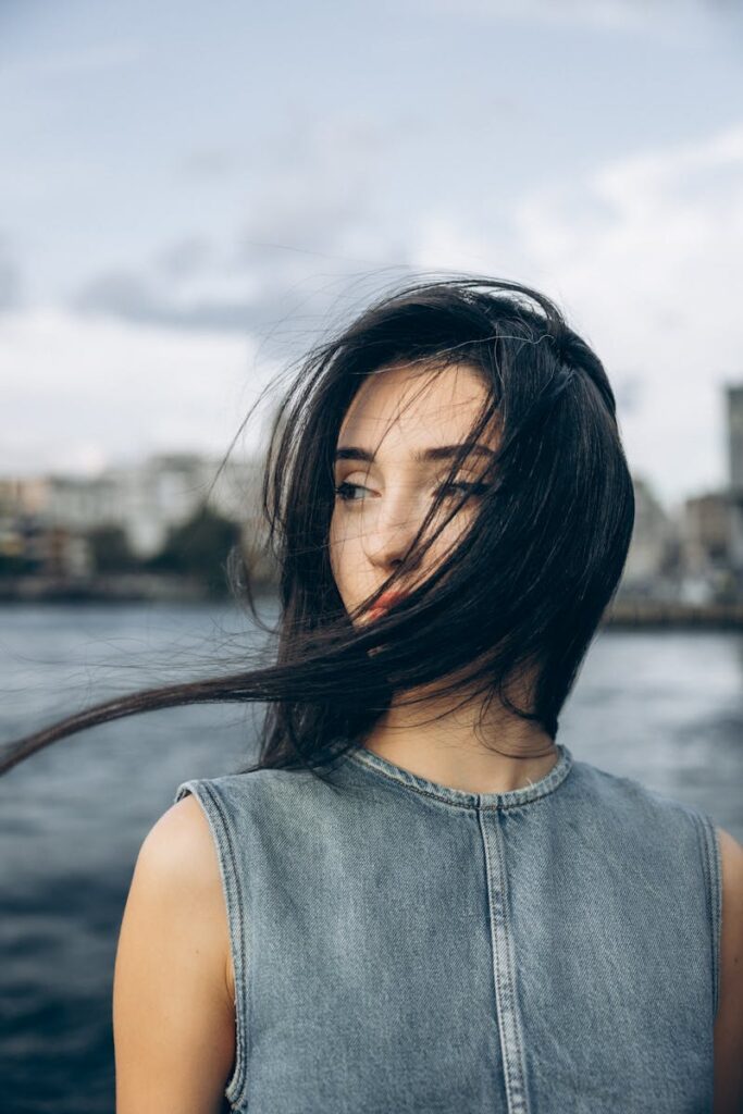 A young woman with flowing hair stands by the Bosphorus in Istanbul, Türkiye.