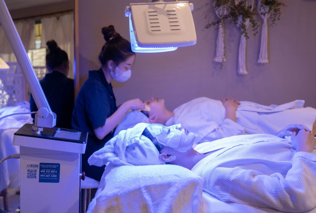 Patients receiving LED light therapy and facial treatment in a spa setting.