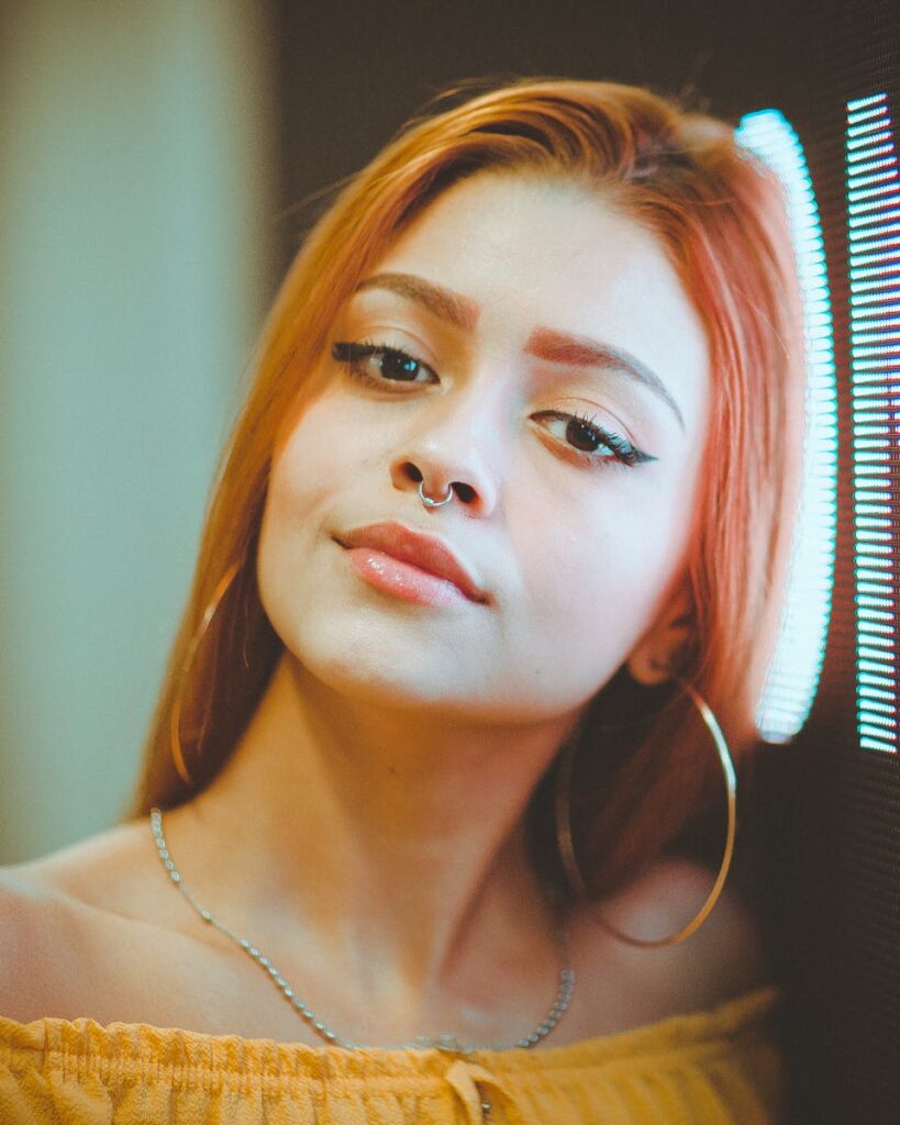 Close-up portrait of a confident woman with a nose ring and striking makeup.