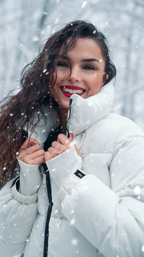 Joyful woman in a puffer jacket, enjoying the snowy winter outdoors.