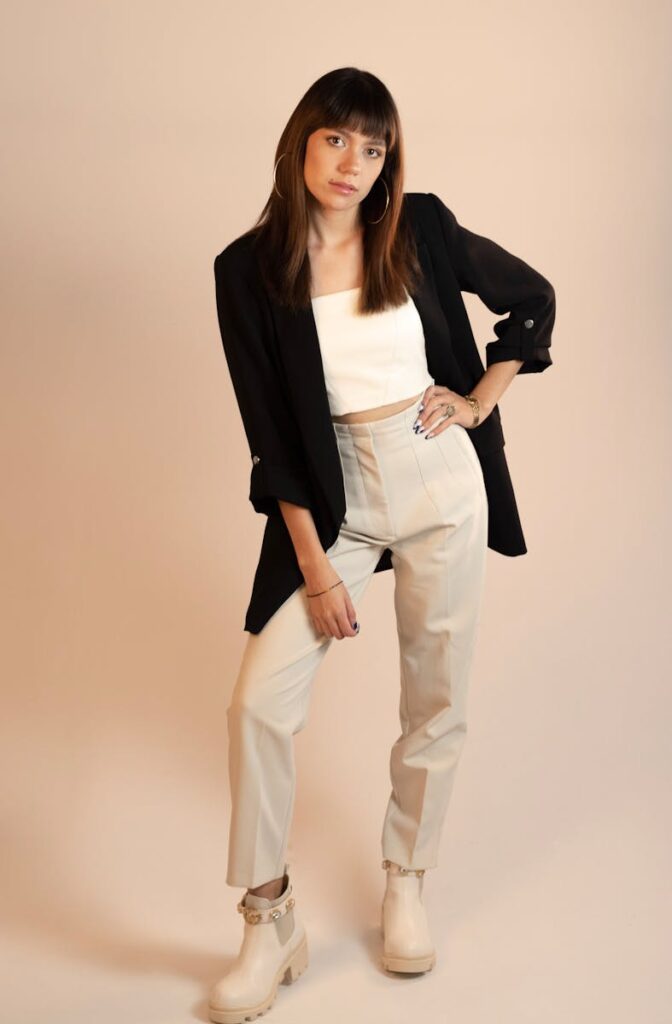 Young woman in modern fashion outfit posing playfully during a studio shoot.